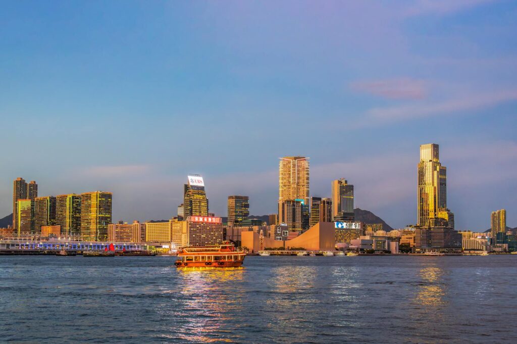 Dramatic view of Hong Kong's skyline and ferry on Victoria Harbour at sunset.
